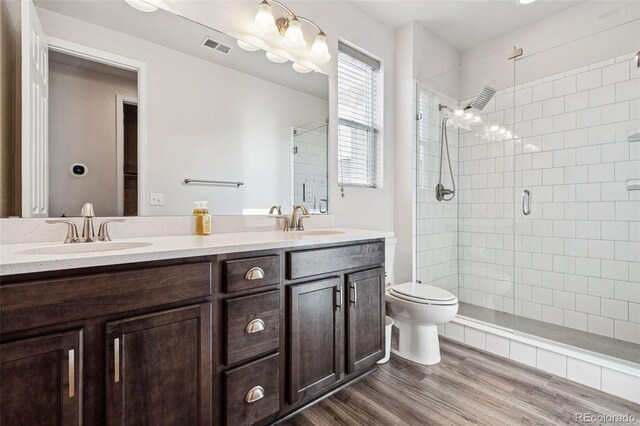 bathroom featuring double vanity, a shower stall, a sink, and wood finished floors