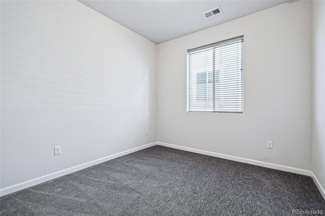 spare room with baseboards, visible vents, and dark colored carpet