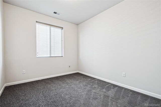 empty room with baseboards, visible vents, and dark carpet