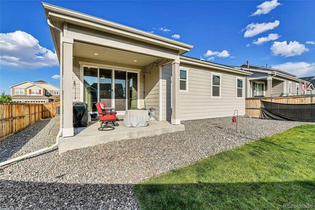 back of house with a patio area, a lawn, and a fenced backyard