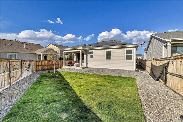 back of house featuring a lawn, solar panels, a patio, a fenced backyard, and a residential view