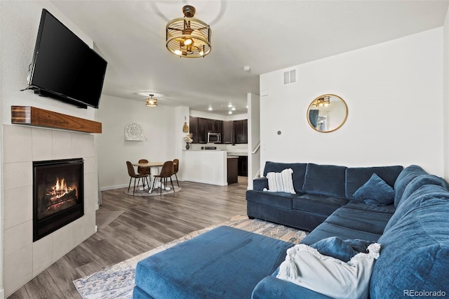 living room with hardwood / wood-style flooring and a tiled fireplace