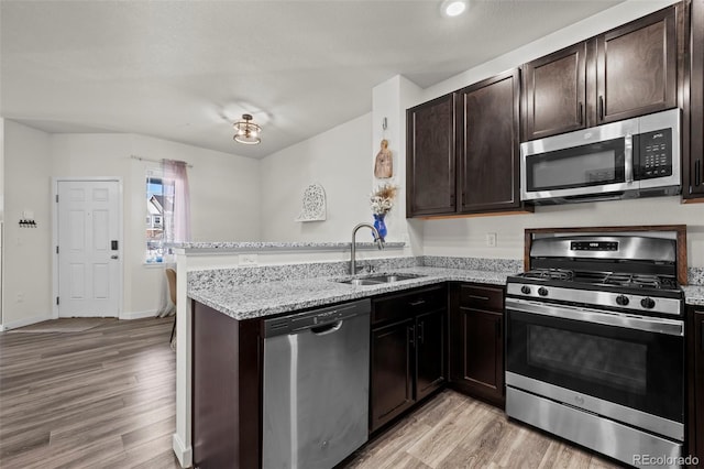 kitchen with light hardwood / wood-style floors, sink, stainless steel appliances, and kitchen peninsula