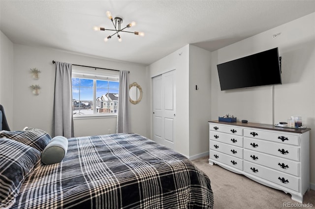 carpeted bedroom with a notable chandelier, a closet, and a textured ceiling