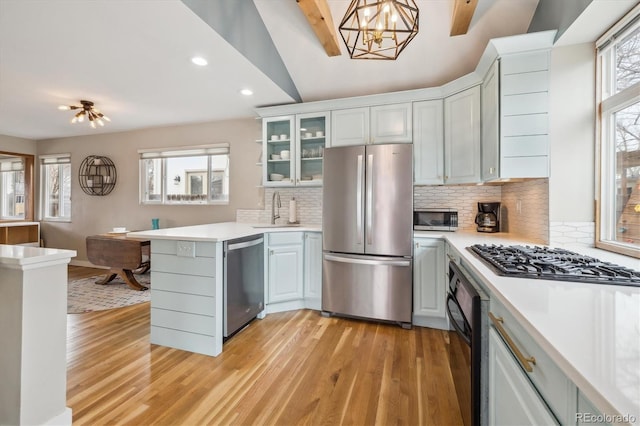 kitchen with hanging light fixtures, a sink, stainless steel appliances, and light countertops