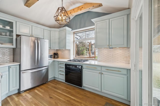 kitchen featuring vaulted ceiling with beams, appliances with stainless steel finishes, pendant lighting, light hardwood / wood-style floors, and backsplash