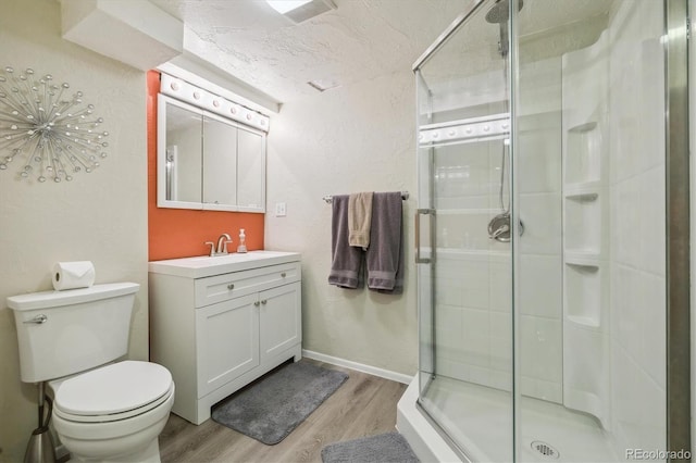 bathroom with hardwood / wood-style flooring, a shower with door, vanity, a textured ceiling, and toilet