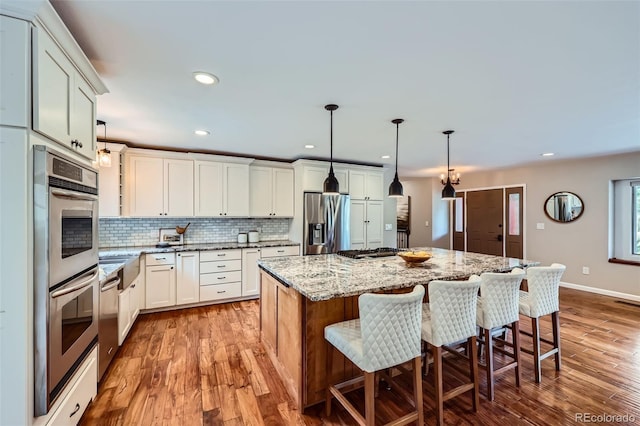 4776 Red Rock Dr, Larkspur, CO 80118 - kitchen featuring stainless steel appliances, tasteful backsplash, a center island, light wood finished floors, and light stone countertops