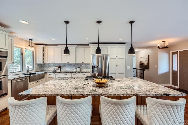 4776 Red Rock Dr, Larkspur, CO 80118 - kitchen featuring stainless steel appliances, dark wood finished floors, a sink, a center island, and backsplash