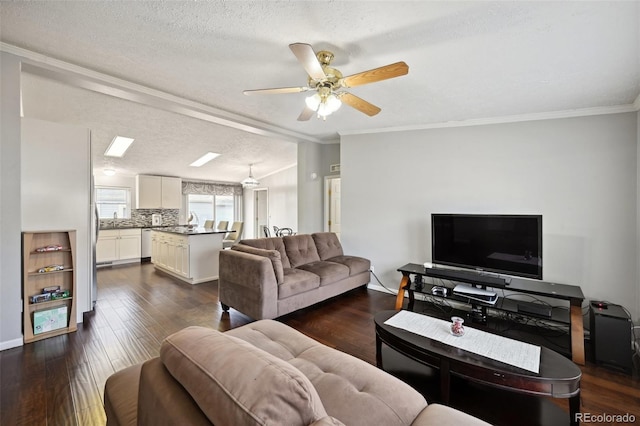 living room with ceiling fan, a textured ceiling, dark wood-type flooring, crown molding, and sink