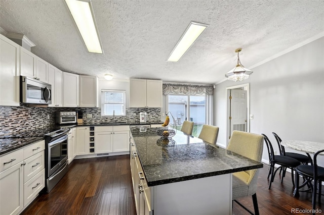 kitchen with appliances with stainless steel finishes, sink, a center island, hanging light fixtures, and dark hardwood / wood-style floors