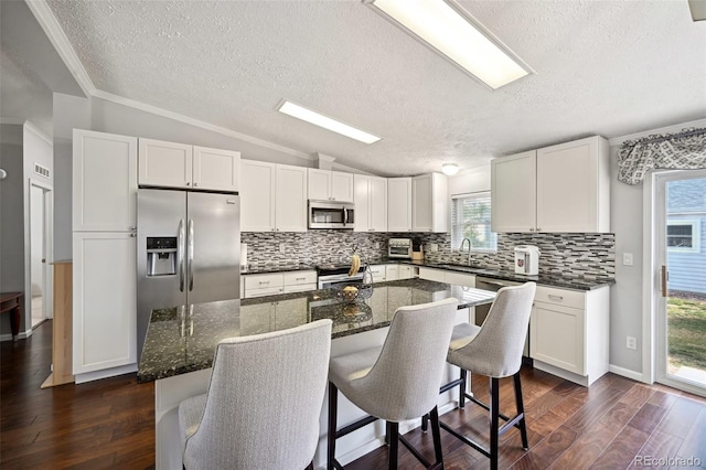 kitchen featuring lofted ceiling, dark wood-type flooring, appliances with stainless steel finishes, and white cabinets