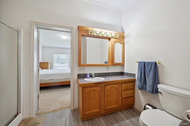 bathroom with hardwood / wood-style flooring, toilet, ornamental molding, vanity, and walk in shower