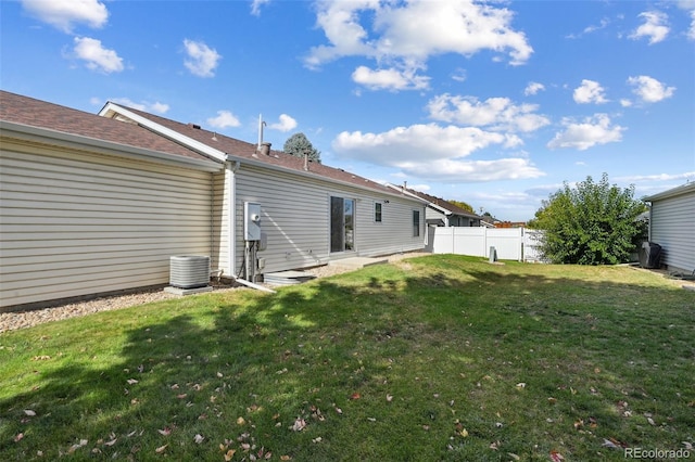 back of house featuring a yard and central AC