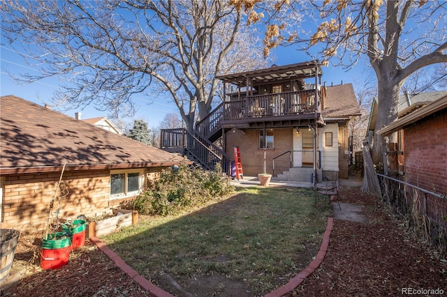 rear view of property with a wooden deck and a lawn