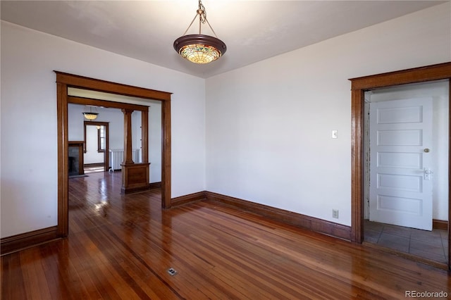 spare room featuring radiator heating unit and dark hardwood / wood-style floors