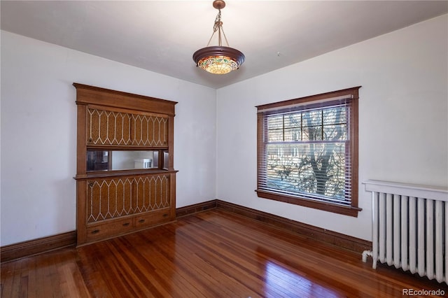 empty room featuring radiator and dark hardwood / wood-style floors