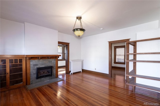 unfurnished living room with dark hardwood / wood-style flooring, a tile fireplace, and radiator heating unit