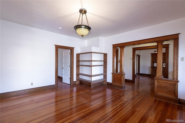 empty room featuring dark hardwood / wood-style floors and ornate columns