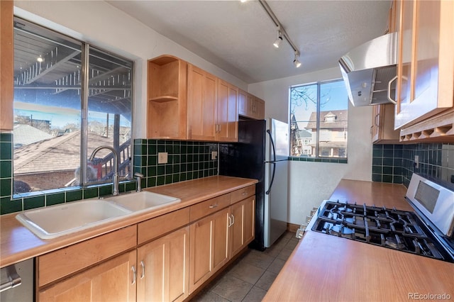 kitchen with extractor fan, light tile patterned floors, gas stove, backsplash, and sink