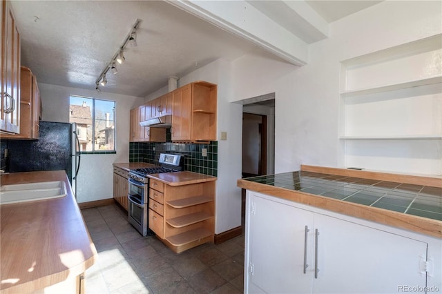 kitchen with rail lighting, tile counters, range with two ovens, sink, and backsplash