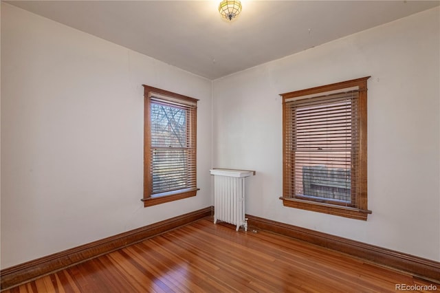 unfurnished room with radiator and wood-type flooring