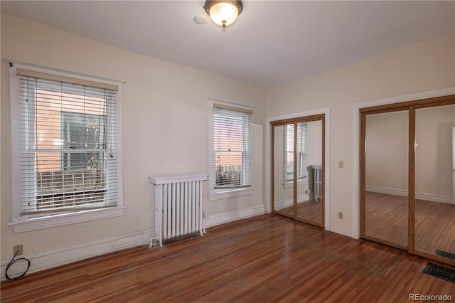 unfurnished bedroom with dark hardwood / wood-style floors and radiator