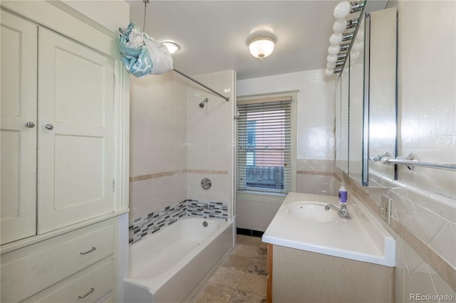 bathroom with tile walls, tiled shower / bath combo, and vanity