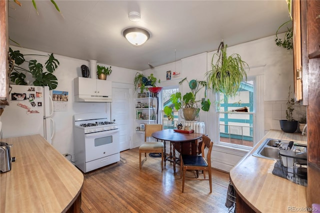 kitchen with white appliances, white cabinets, sink, and hardwood / wood-style floors