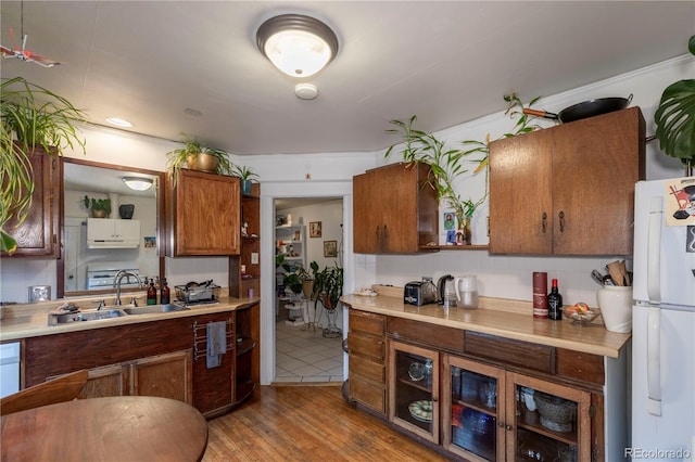 kitchen with sink, light hardwood / wood-style flooring, white fridge, and backsplash