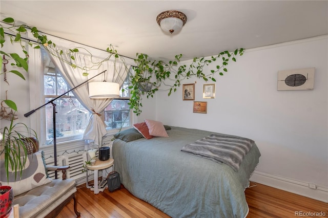 bedroom with ornamental molding and wood-type flooring