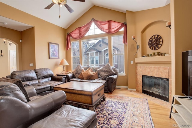 living room with ceiling fan, light hardwood / wood-style floors, lofted ceiling, and a fireplace