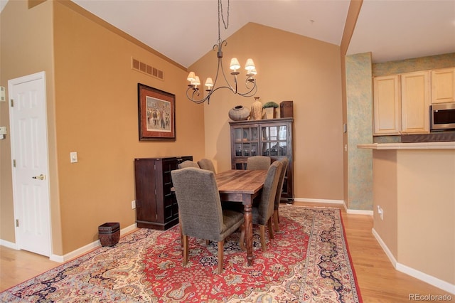 dining area featuring an inviting chandelier, light wood-type flooring, and vaulted ceiling