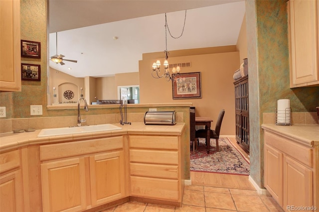 kitchen with sink, kitchen peninsula, light brown cabinetry, ceiling fan with notable chandelier, and light wood-type flooring