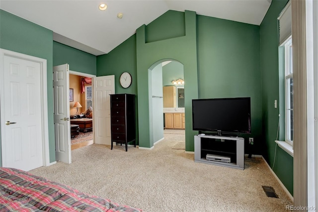 carpeted bedroom featuring ensuite bathroom and vaulted ceiling