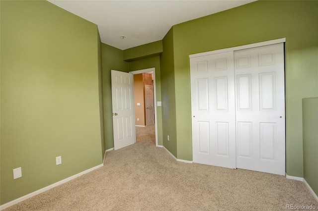 unfurnished bedroom with light colored carpet and a closet