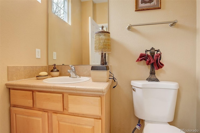 bathroom with vanity, toilet, and backsplash