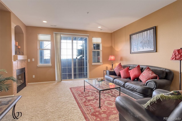 carpeted living room featuring a tiled fireplace