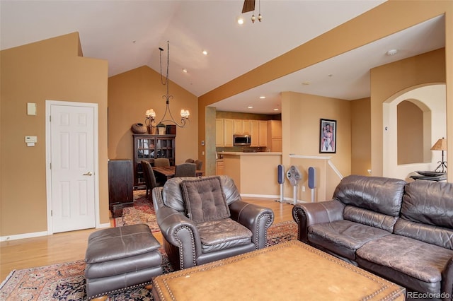 living area with light wood finished floors, arched walkways, vaulted ceiling, recessed lighting, and baseboards