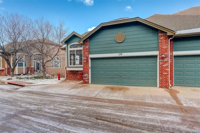 ranch-style home featuring brick siding, driveway, and a shingled roof