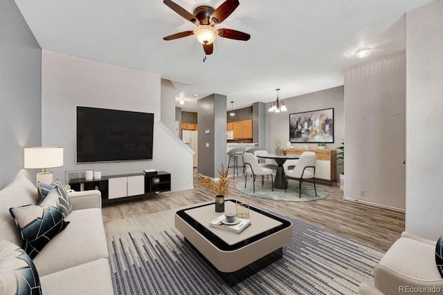 living room featuring ceiling fan with notable chandelier and wood finished floors