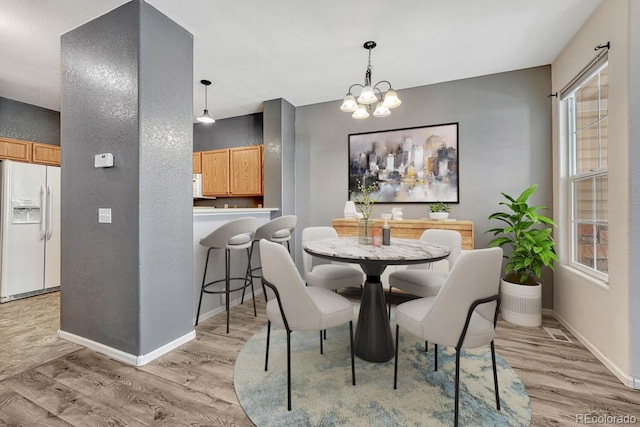 dining space featuring an inviting chandelier, light wood-style flooring, and baseboards