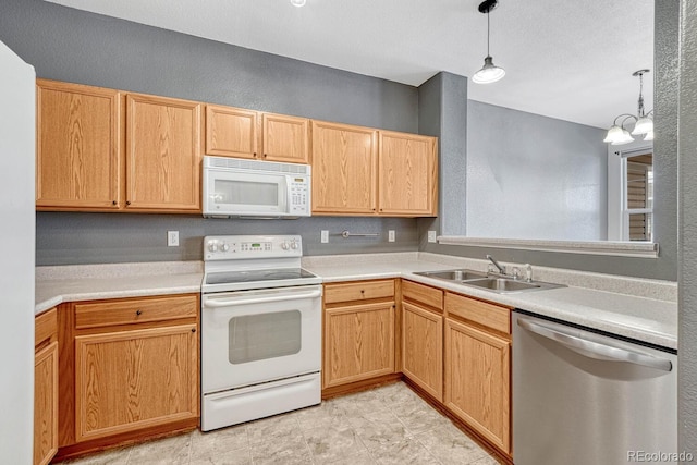 kitchen with a notable chandelier, a sink, white appliances, light countertops, and hanging light fixtures