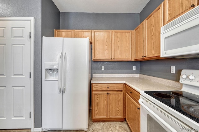 kitchen with a textured wall, white appliances, and light countertops