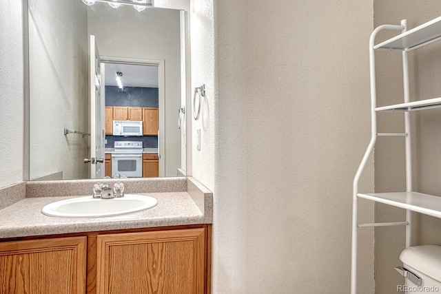 half bath featuring vanity, toilet, and a textured wall