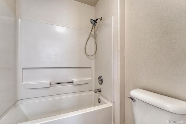 full bath featuring toilet, washtub / shower combination, and a textured wall