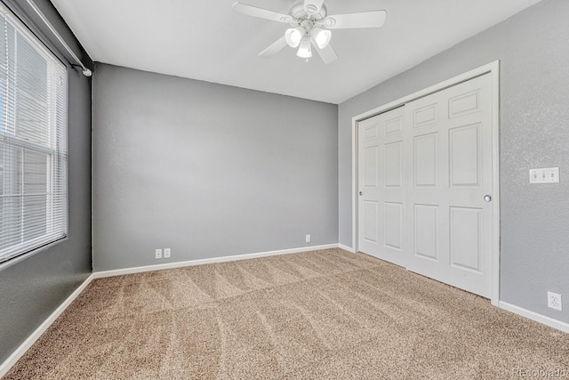 unfurnished bedroom featuring a closet, baseboards, carpet, and a ceiling fan