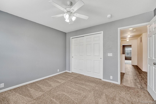 unfurnished bedroom with ceiling fan, carpet, a closet, and baseboards