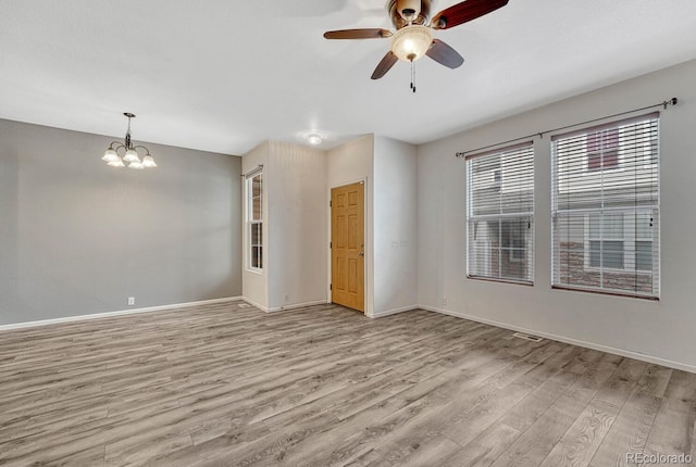 unfurnished room featuring ceiling fan with notable chandelier, baseboards, and light wood finished floors