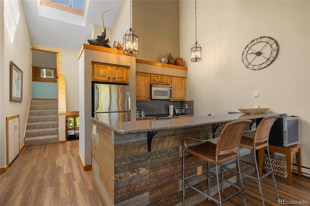 22300 US Highway 6 Unit 1746, Dillon, CO 80435 - kitchen featuring stainless steel appliances, high vaulted ceiling, a breakfast bar, wood finished floors, and brown cabinetry